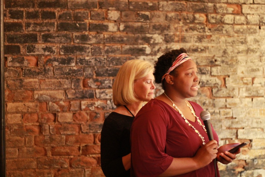 Shandreanna speaks at CYC Trivia Night with mentor Lori beside her