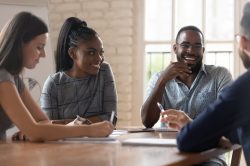 Head shot happy mixed race young business partners having fun during meeting with clients. Positive african american millennial manager laughing, telling jokes, enjoying pause time with diverse colleagues.